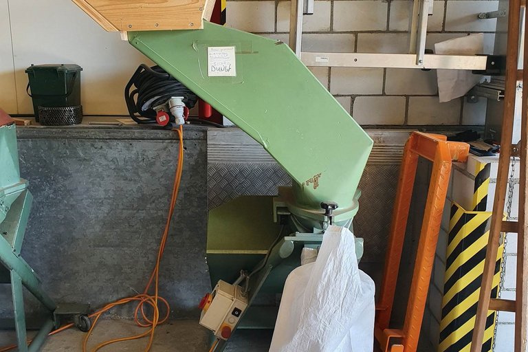 Korkmühle schreddert die Korken in Granulat und füllt sie in einen Sack ab