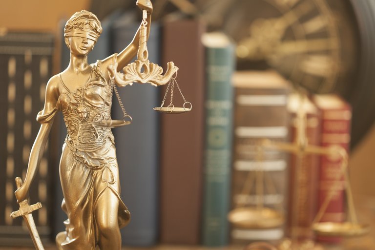 Gesetze und Rahmenbedingungen Justitia vor Bücher und Gesetzeswaage