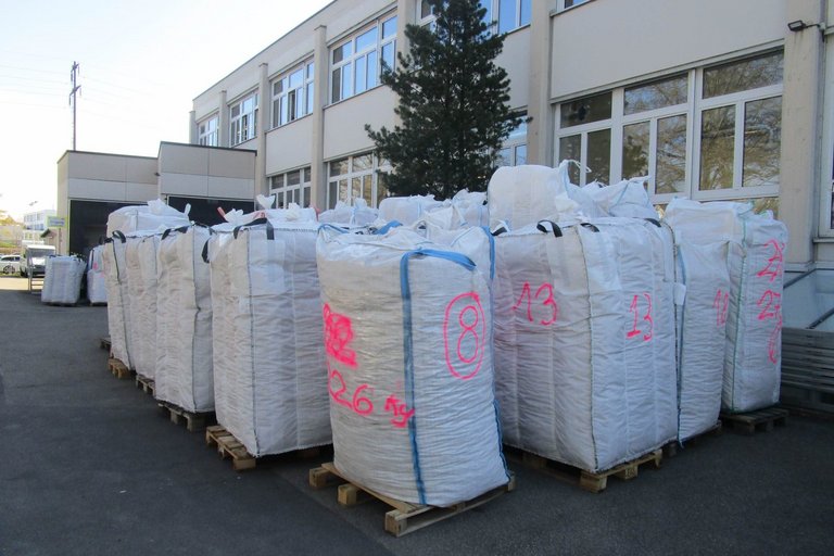 Grosse abgepackte Säcke lagern vor der Korkmühle im Freien. 